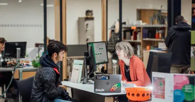 Male students speaking with female support staff at a desk