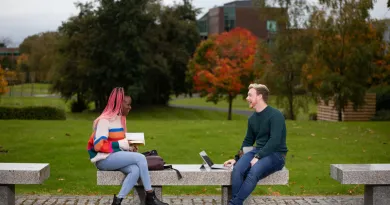two students seated on a bench in the plaza on campus 