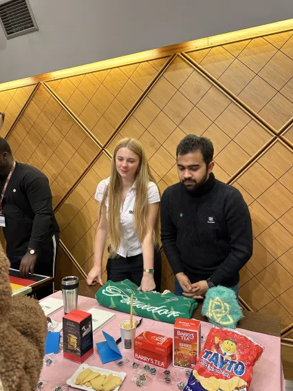 Síofra and Abid presenting the Ireland table with Tayto, tea, and other snacks