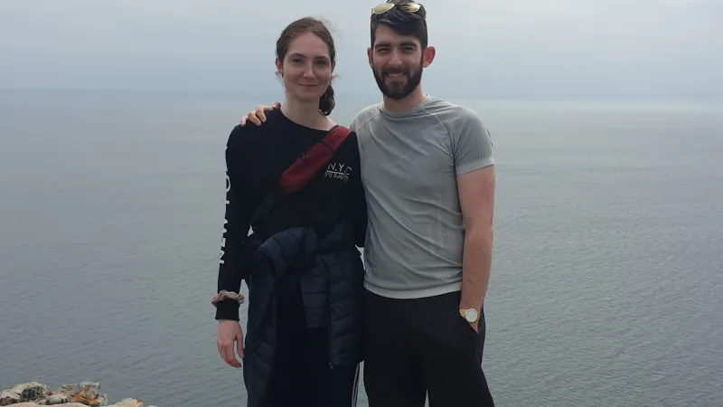 A woman and a man standing beside each other with the sea in the background