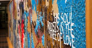 A photo of a multi-coloured mosaic wall featuring the words "his soul roosts in the tree of love"
