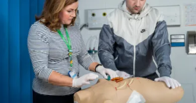 two medical students practice on a medical dummy 
