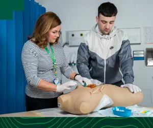 two medical students practice on a medical dummy 