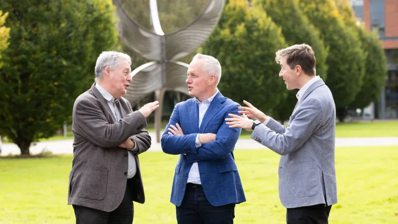 image of three men talking to each other in an outdoor setting 