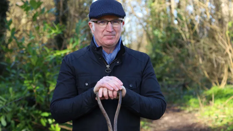 photo of a man in outdoor setting leaning on a shovel