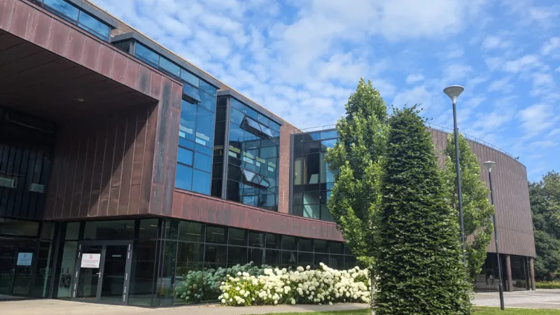 exterior of library building with flowers and tress