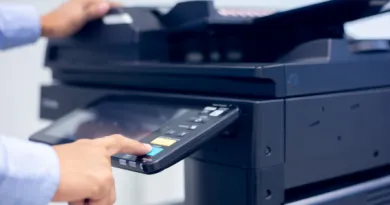 A person is using a printer by pressing the keypad attached to the machine.
