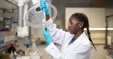A woman in a lab in a white labcoat using a pipette