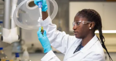 science student in lab coat  working on research in UL