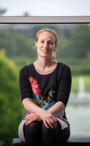 Woman in floral dress sitting with window in background