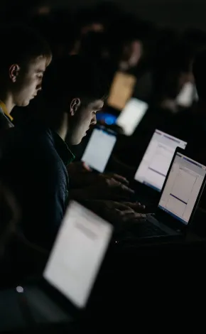 students at a lecture lit by laptop